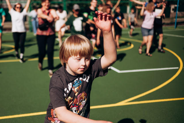 A young camper on the sport court raising a hand for a high five